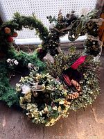 Five Christmas wreaths gathered together showing various decorative elements such as pinecones, berries, leaves, and ribbons.