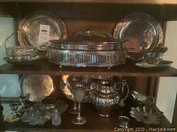 Assortment of all silver-plated pieces displayed on two shelves
