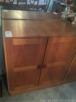 Front view of teak wood dining cabinet showing double doors and wooden round handles.