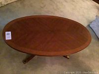 Full top-down view of the oval-shaped wood coffee table showing surface and legs on carpet.