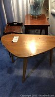 Photo showing the kidney-shaped wooden table with tapered legs and a small tray table behind it.