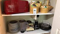 Photo showing red KitchenAid toaster, ceramic canisters with woven basket lids, Osterizer blender, Hamilton Beach pulser, cast iron pan on two shelf racks