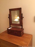 Full view of wooden dressing mirror with rectangular frame and two-drawer wooden base stand