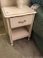 Pair of white nightstands placed beside beds, showing overall condition and size.