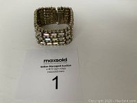 Bracelet standing upright showing fold-over clasp and safety chain