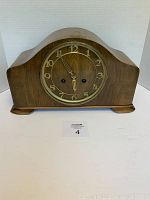 Front view of the wooden mantel clock with brass frame attached to the clock face.