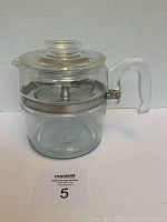 Vintage Pyrex glass coffee percolator assembled showing glass pot with handle, glass lid, and metal filter basket inside.