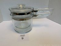 Side view of the assembled double boiler showing clear glass with stainless steel strip, glass handles and lid on top