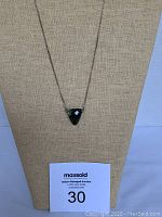 Front view of silver chain necklace with triangular labradorite stone pendant against beige fabric display showing chain, pendant, and clasp type