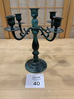 Front view of verdigris 5-arm candelabra showing the base, curved arms, and candle holders.