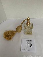 Heavy crystal perfume atomizer with gold-colored detail, beige fabric spray bulb with tassel, standing upright with label showing approximately 5 inches high.