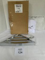 Photo showing the shower shelf with the original box and instructions on a white background.