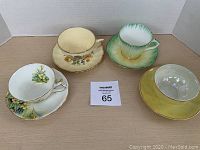 Four teacups and saucers arranged on table, showing overall view and condition