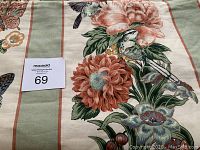 Close-up photo showing folded part of the bedspread with floral and butterfly design, highlighting the fabric pattern and colors.