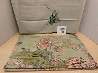 Photo showing the folded Japanese printed fabric panel with visible architectural and floral motif, alongside the pale green table topper with embroidery visible in the background.