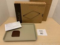 Photo of boxed Pampered Chef small baking pan, booklet, and mini scraper arranged on a neutral surface showing all included items.