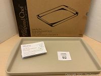 Photo of the large beige Pampered Chef baking pan with instruction booklet and box behind it.
