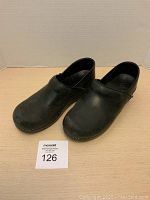 Photo showing angled view of both black leather clogs polished side by side.