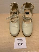 Front view of both cream colored closed toe sandals with crossed straps and ankle buckles showing toe and strap details.