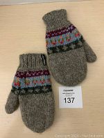 Pair of fleece lined wool mittens with colorful knit pattern on ribbed cuffs and fleece lining, laid on a flat surface with MaxSold auction card labeled 137.