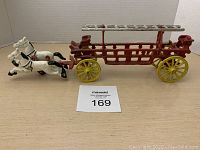 Full view of the firetruck with two white horses and detachable ladder on a wooden surface.