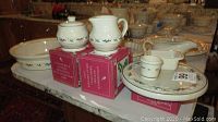 Photo of the full set of Longaberger Christmas pottery showing various items including 11-inch bowl, cream and sugar set, oval platter, and small serving dishes stacked and displayed on a countertop.