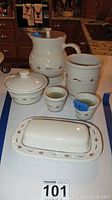 All 6 pieces of Longaberger pottery kitchen set arranged on table with visible floral motif and white glaze.