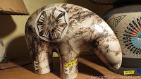 Front and left side view of the plaster bear sculpture showing carved geometric designs and horsehair veining.