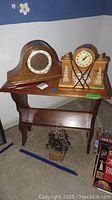 Photo of vintage Welby mantel clock, United brand clock with fireplace detail, and wooden table with bookshelf on carpeted floor near corner with blue floral wall decoration.