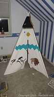 Full view of the assembled children's teepee in a striped room corner, showing the canvas exterior and PVC pipe supports.