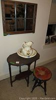 Vintage piano stool, wood table with sign marked 100, ceramic bowl and pitcher on table, wood framed window mirror reflect background