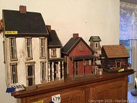 Front view of all 5 wooden bird houses displayed on a wooden piece of furniture, showing size and variety