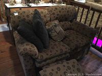 Front view showing entire loveseat with upholstery pattern and accent pillows.