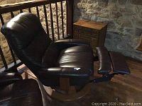 Full view of dark brown leather recliner on wood swivel base