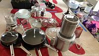 Overview of assorted kitchenware items including pots, pans, small appliances, glass lids, and dinnerware.
