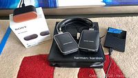 Sony WF-1000XM3 box and Harman/Kardon headphones laid out on floor