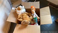 Open cardboard box containing a large stuffed tiger and George Jetson doll.