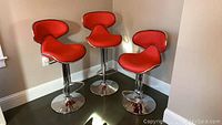 Three red bar stools grouped against wall
