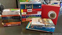 Wide shot of the lot showing a stack of SAT, ACT, and AP prep books along with novels from Edward Eager and Cassandra Clare, plus educational and journal-type books.