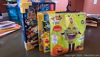 Photo showing two LEGO sets (Atlantis and Creator Beach House) still in original boxes, and the Annoying Orange Pear costume in its packaging on a hanger.