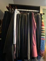 Various women's suit jackets, dress shirts, sweaters including a colorful striped knit sweater on hangers