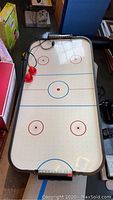 Full view of the tabletop air hockey game showing playing surface, paddles, and puck.