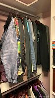 Photo of jackets and tops hanging on closet rod showing variety of clothing including Champion jacket.