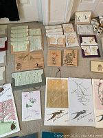 Photo showing assorted woodblock print greeting cards, yearly calendars signed by Gwen Frostic with botanical and bird designs.