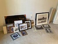 View showing framed and unframed art prints, photographs, and original line drawings arranged on floor, including black leather portfolio cases.