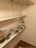 Assorted clear glass vases, wooden bases, and decorative stones arranged on a white shelf along with boxed E-MaxiLuminator acolytes for floral design.
