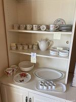 Cabinet shelves with assorted dishware including Villeroy & Boch Albertina floral cups and saucers, white teapot, Lenox Butterfly Meadow plates and mugs