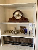 Wide view of mantel clock on top shelf and decorative items on middle shelf
