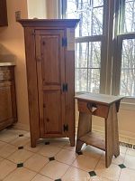 Front view of wood pie safe cabinet and small wood table by window