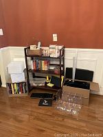 Wide view showing collapsible dark wood shelf with books, card organizers, keyboard, and mouse on floor